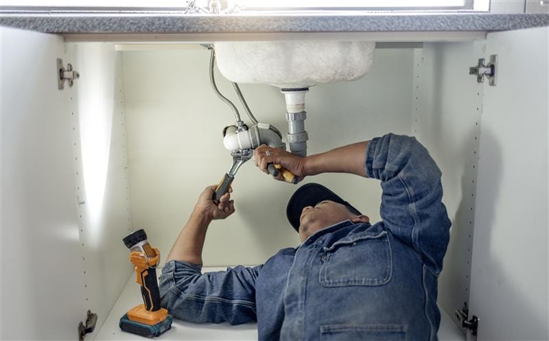 Plumber repairing kitchen sink drain pipes in Lawrenceville, Georgia