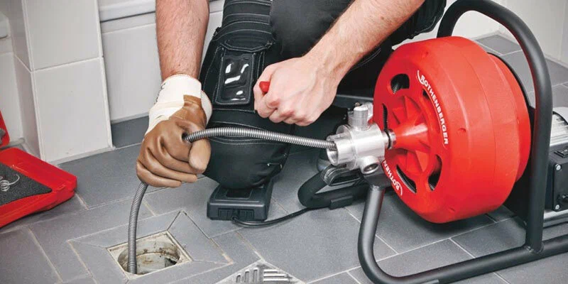 Plumber using a drain-cleaning machine in Lawrenceville